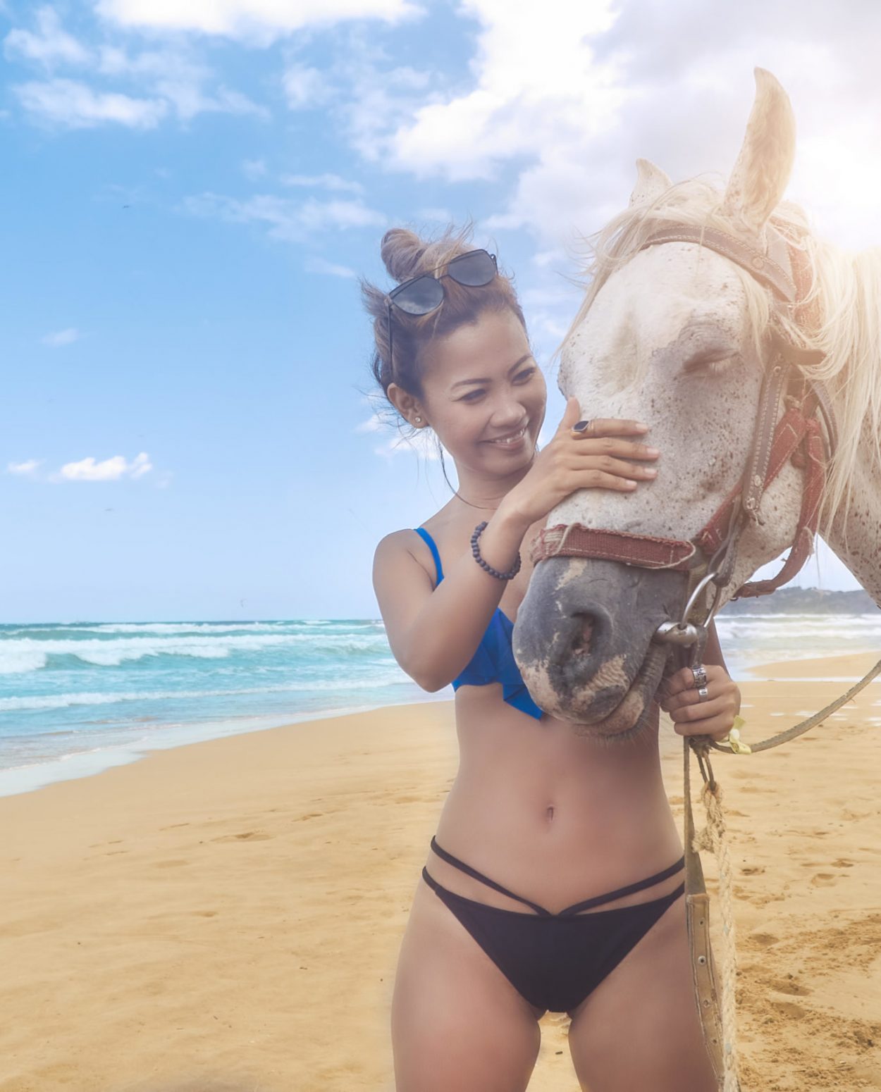 Woman stroking a white horse on the beach